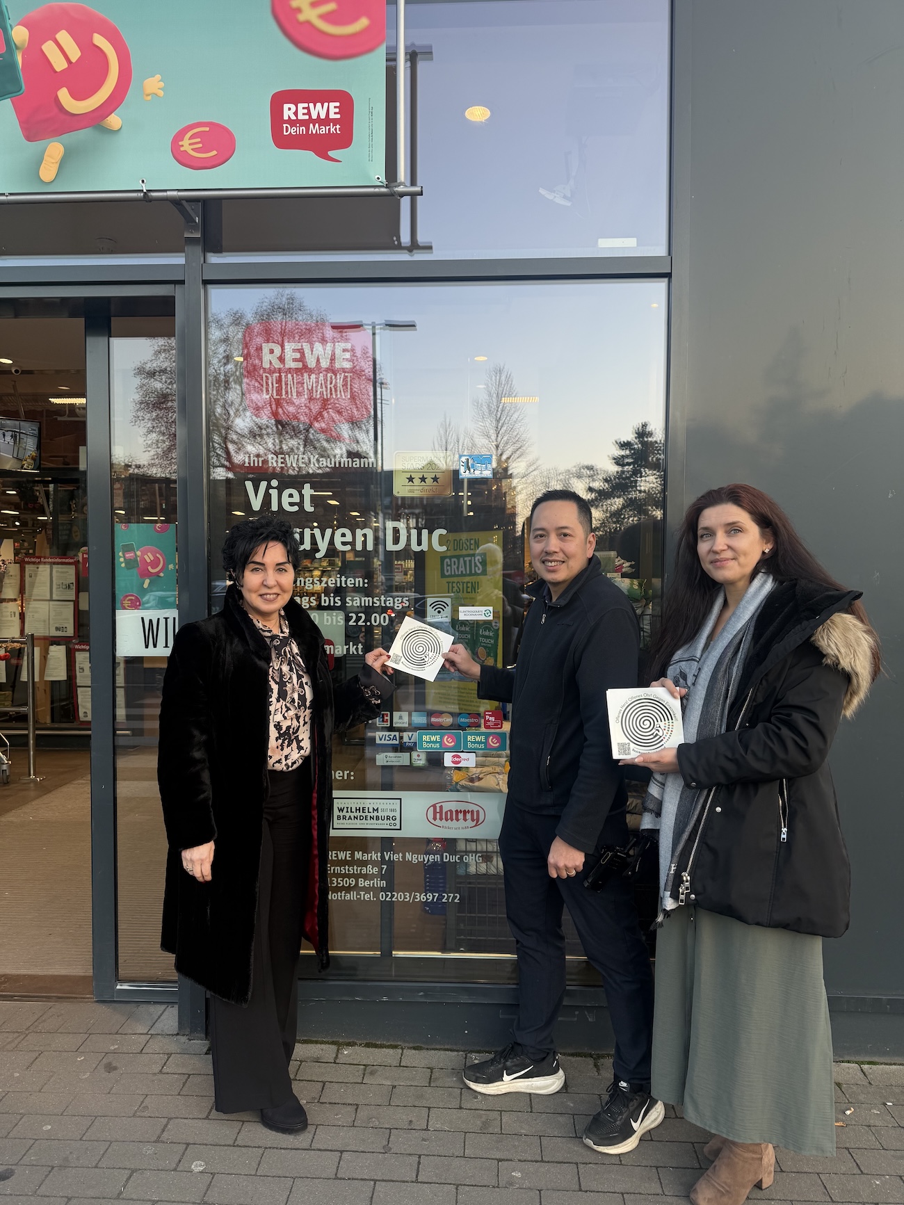 Bezirksbürgermeisterin Emine Demirbüken-Wegner, Herr Duc Viet Nguyen und Einsamkeitsbeauftragte Katharina Schulz beim Anbringen des Stickers gegen Einsamkeit